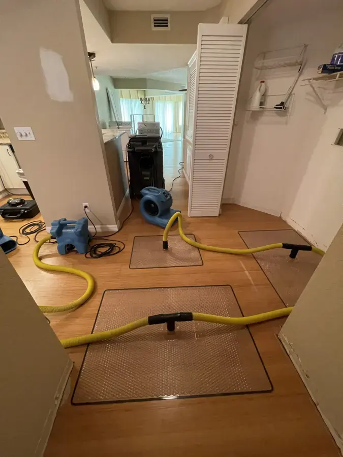 Floor drying mats and yellow hoses on a hallway floor with air movers