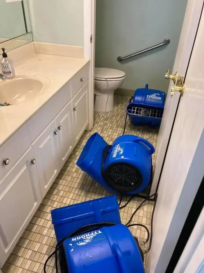 Air movers on a small-tile bathroom floor beside the vanity