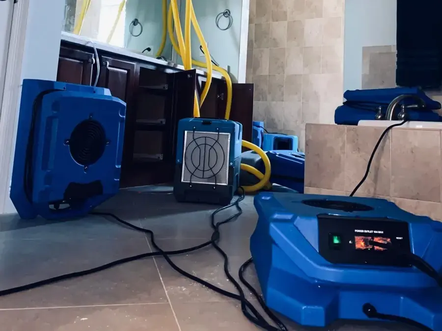 Blue drying equipment and hoses set up on a tile bathroom floor