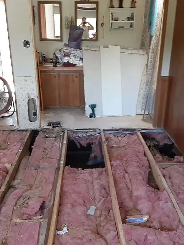 Manufactured home floor opened to the joists and the wet insulation below